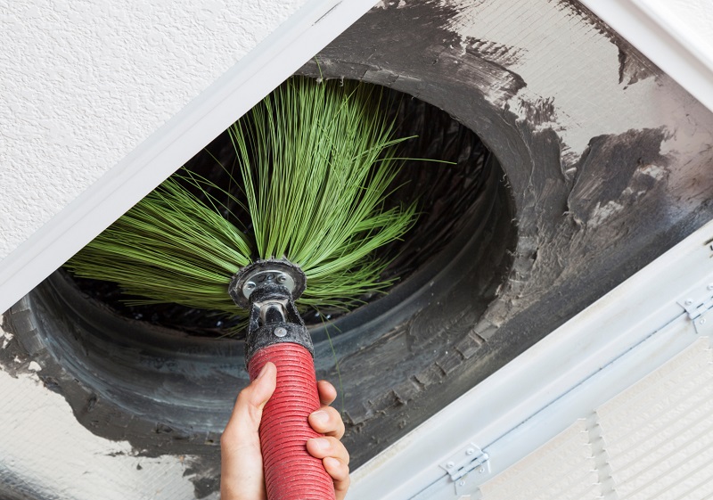 An HVAC technician cleaning an air duct