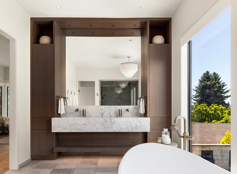 Bathroom with large mirror, plus multiple types of lighting recessed, task, chandelier, and lots of natural light