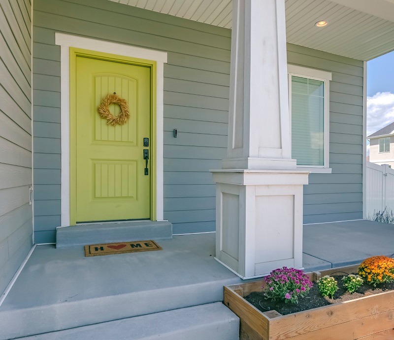 Home with yellow front door and craftsman style porch and columns