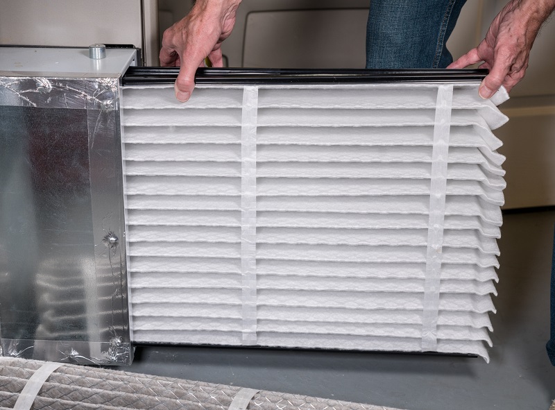 New air filter being placed into a home furnace