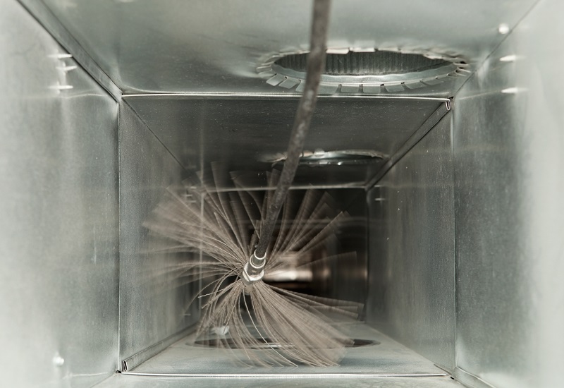 Residential HVAC duct being cleaned with a power brush