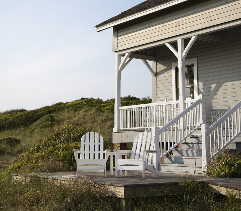 Traditional coastal house with front deck, surrounded by protective natural grass and ground covering