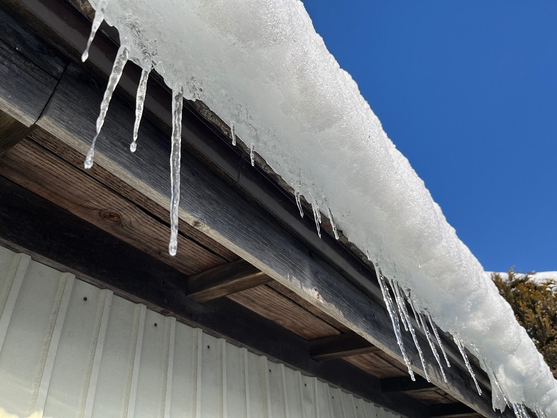 Frozen snow and icicles on roof and rain gutter of house
