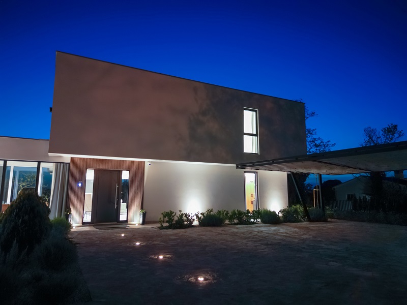 Modern home with uplighting and landscape lighting running toward front door