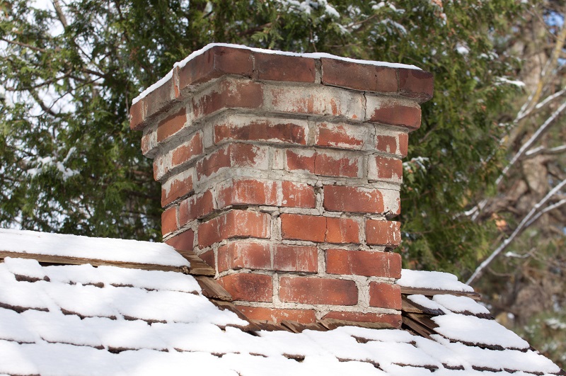 Old brick chimney with cracks during the winter