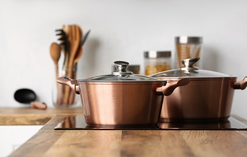 Shiny copper cooking pots on induction stove