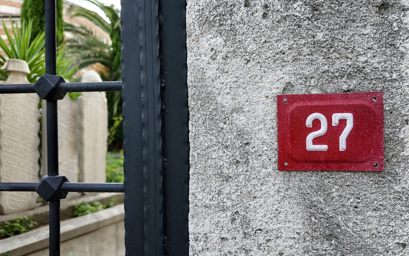 Stone wall and iron gate with red address plate
