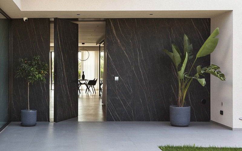 Oikos Synua safety pivot door in gray, perfectly matching the stone cladding a custom designed home