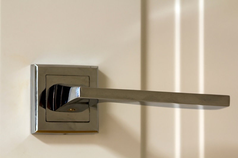 Modern stainless steel lever door handle on wooden door