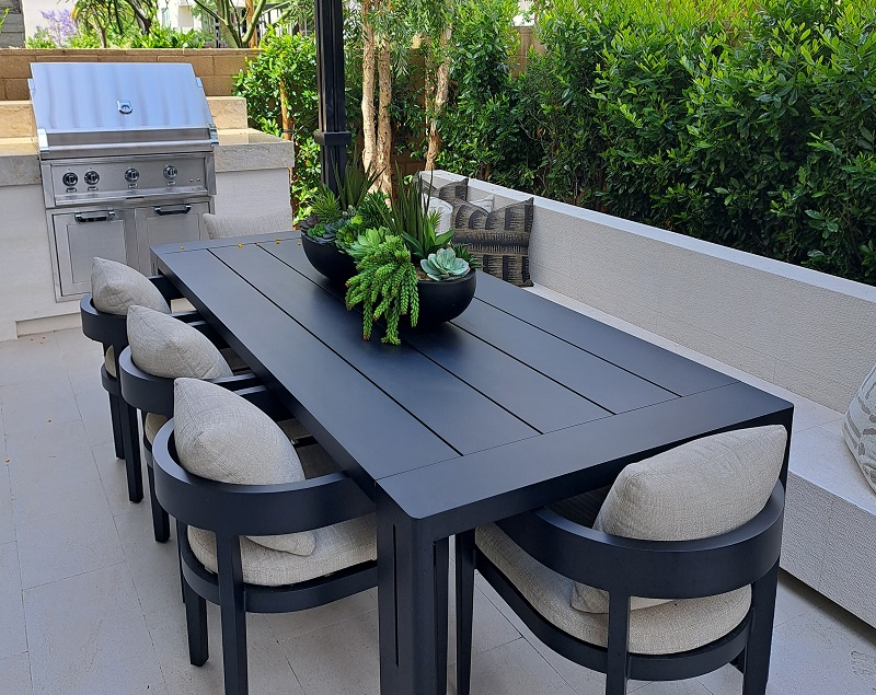 Modern fully furnished backyard patio with dining table and grill