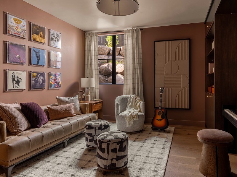 Music room with a tufted leather sofa, a wall of framed vinyl records, an acoustic guitar, and a piano